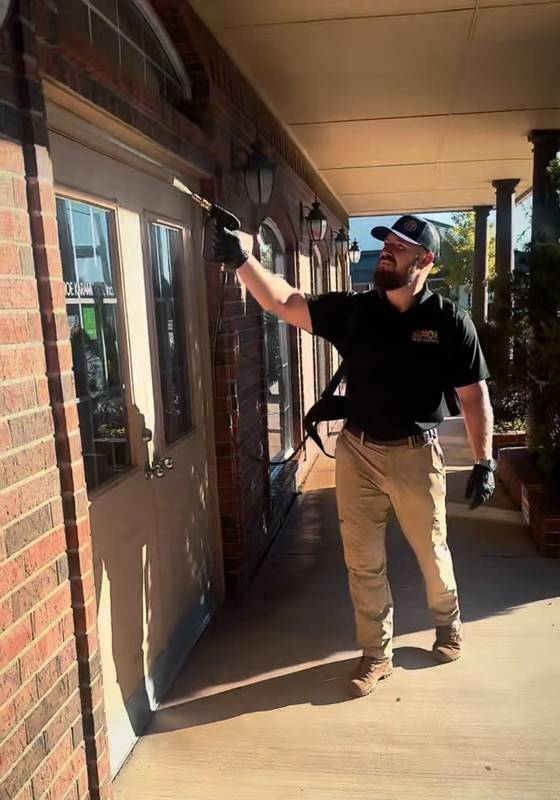 Technician treating the eaves of a brick-front home